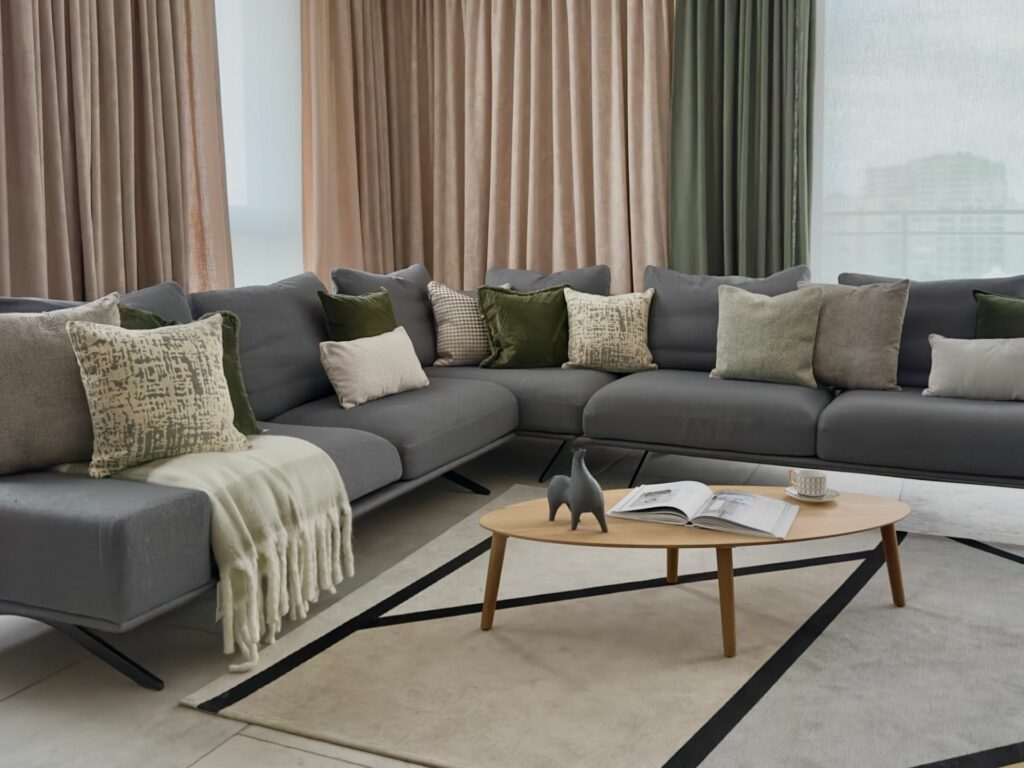 Szara sofa narożna z dekoracyjnymi poduszkami i stolikiem kawowym