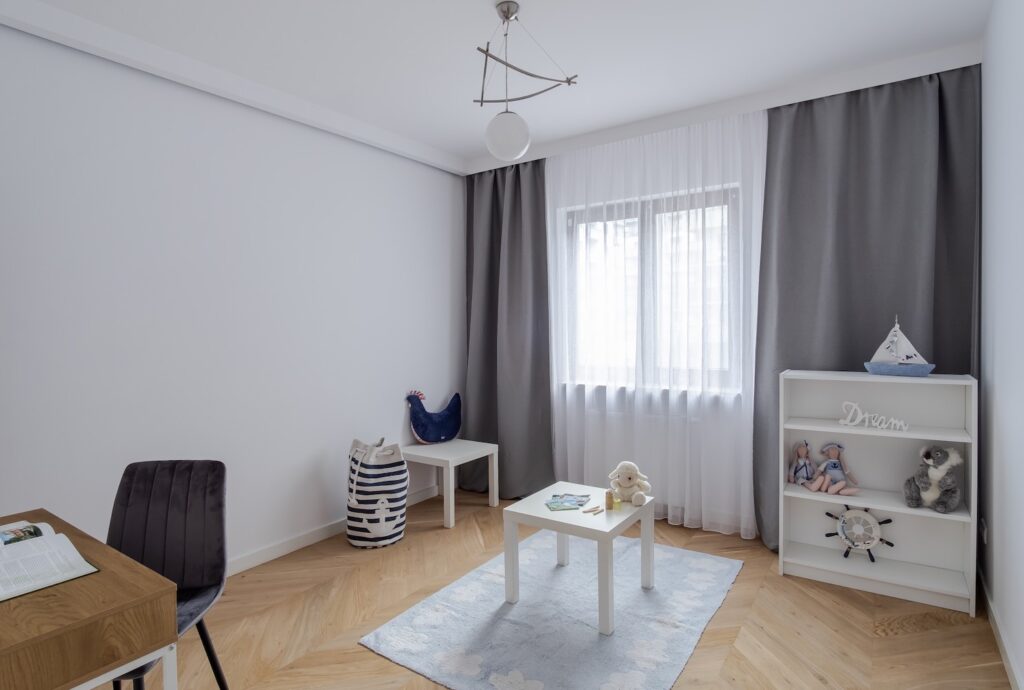 Jasny pokój dziecięcy z biurkiem i zabawkami po home stagingu.