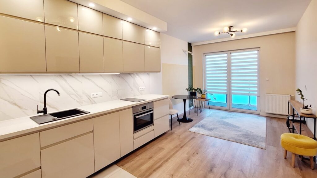 Jasna kuchnia z marmurowym wykończeniem i oknem balkonowym – home staging Piaseczno