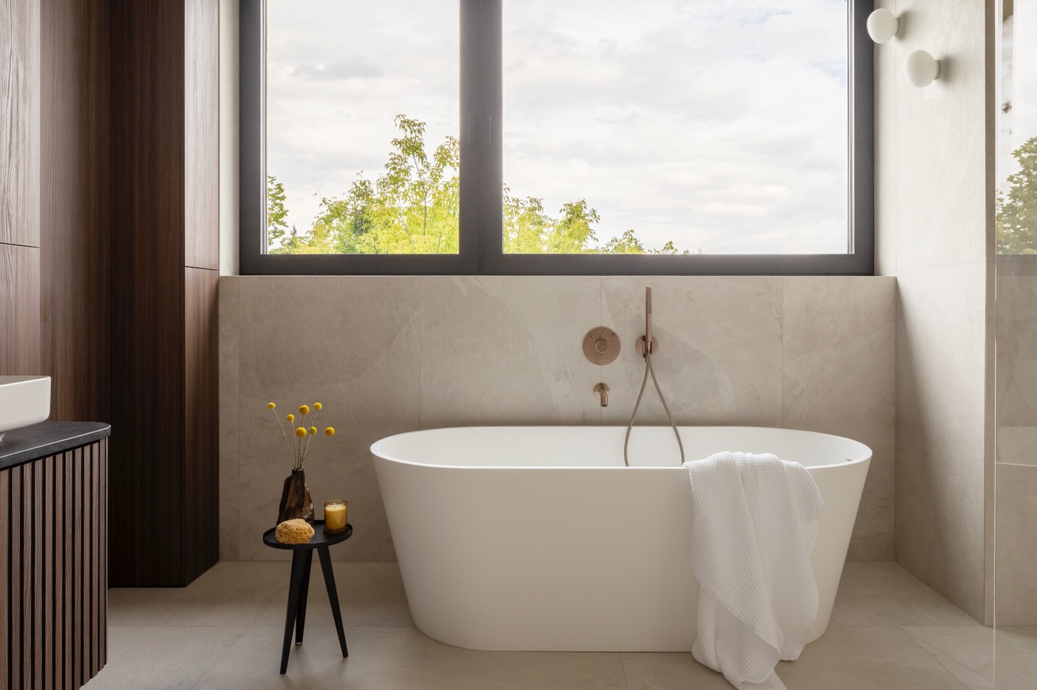 Jasna łazienka z wanną wolnostojącą i widokiem na zieleń