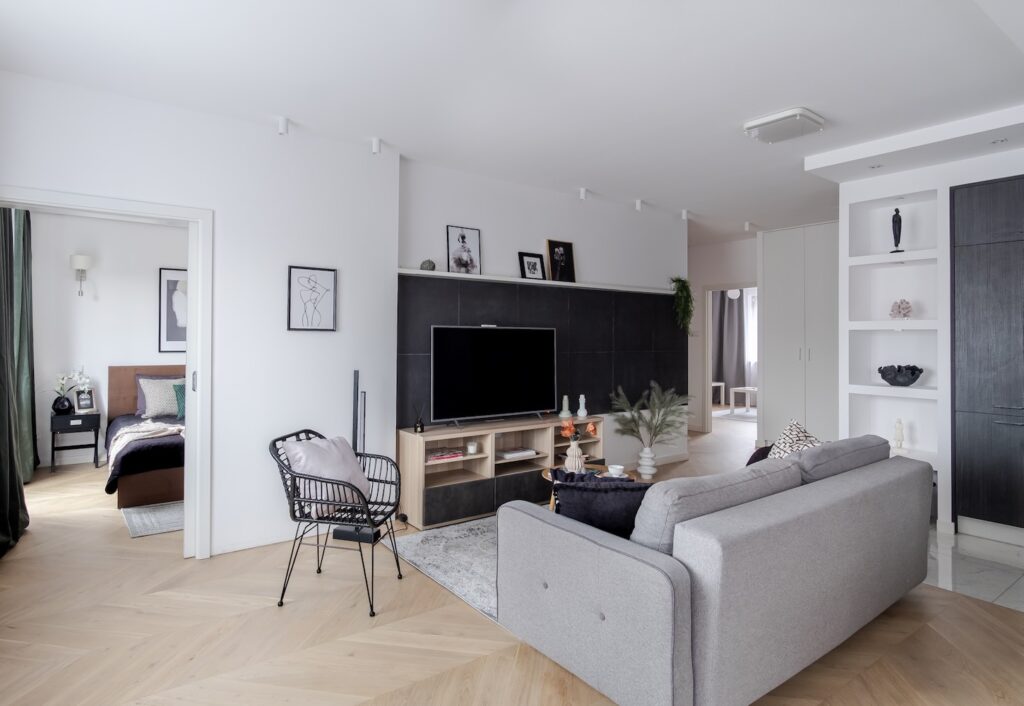Nowoczesny salon z szarą kanapą i telewizorem po home stagingu.