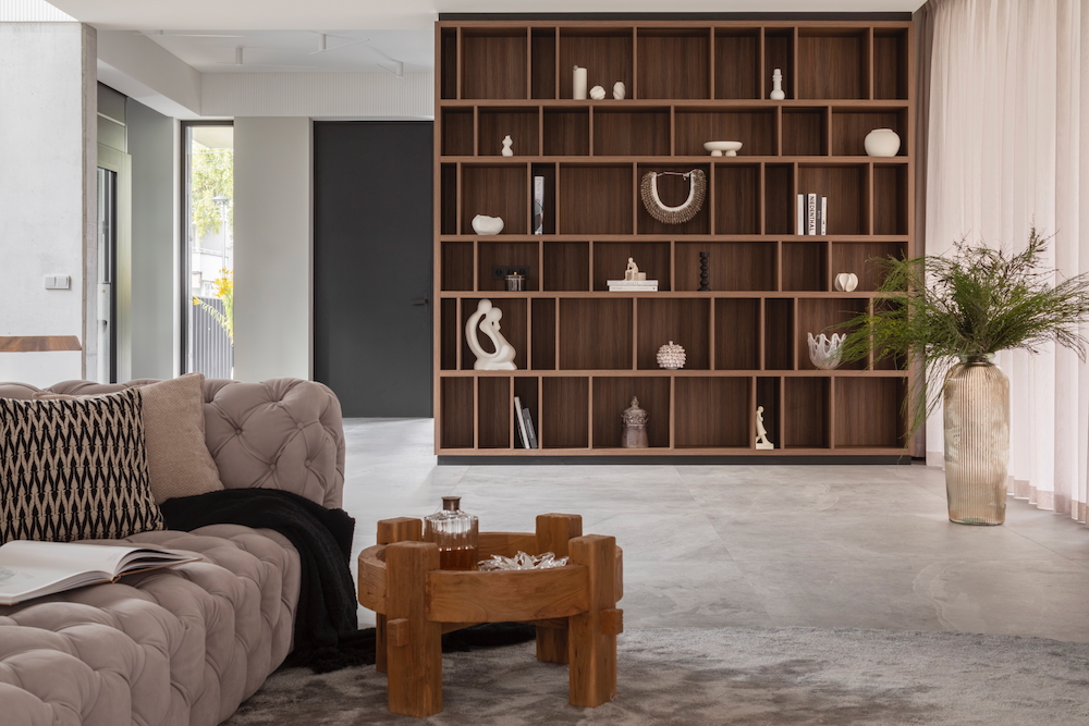 Elegancki salon z dużym regałem z drewna i beżową sofą pikowaną