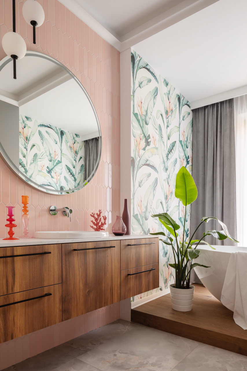 Nowoczesna łazienka z różowymi płytkami typu chevron, tapetą w liście egzotyczne i wolnostojącą wanną – profesjonalna stylizacja wnętrz.